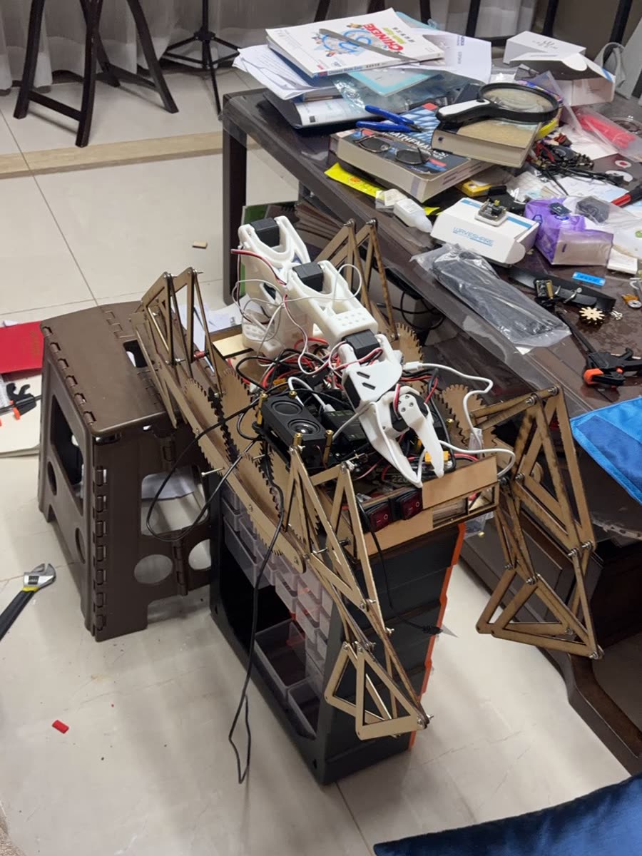 Assembled Jansen-linkage walker: laser-cut plywood triangular legs and frame plates on a tiled workshop floor, with a motor and gearbox mounted at the top of the frame
